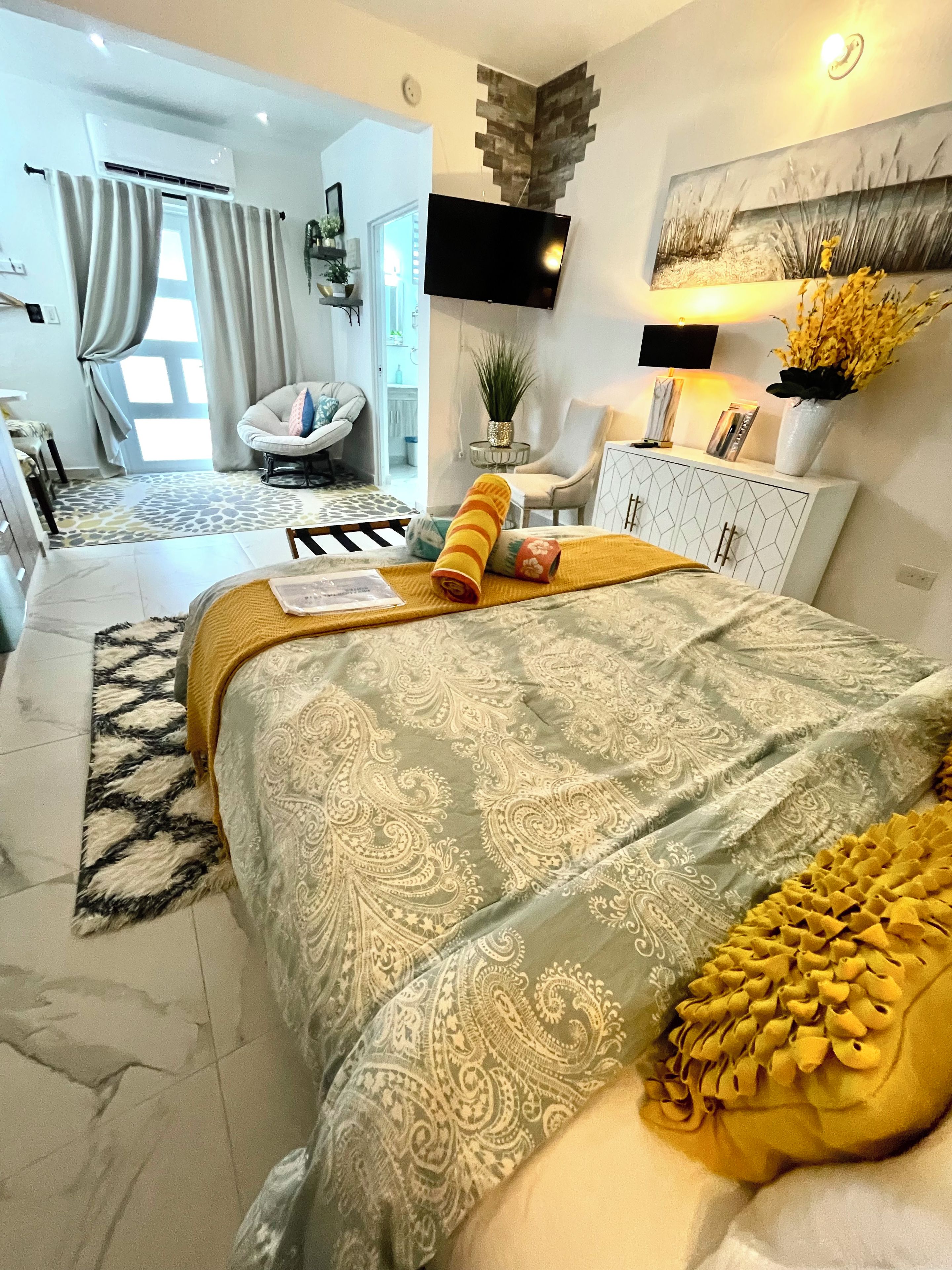 A modern bedroom with a large bed, a flat-screen TV, and a decorative wall piece.