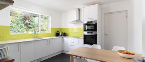 A modern kitchen with white cabinets, a black oven, and a window with a view of greenery.
