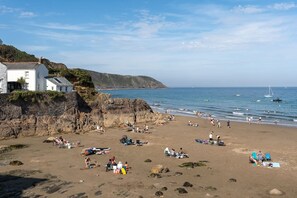 A beach with people sunbathing and swimming, rocky cliffs, and boats in the water. - Modern Home & Garden with Parking, Gorran Haven (Gorran Haven)