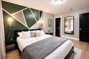 Una camera da letto moderna con un letto, lampade da comodino, un comodino, uno specchio e una porta.
