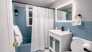 A bathroom with a bathtub, a sink, a toilet, and a shower curtain. - Lovely 6-bedroom apartment with AC in vibrant Queens (Queens)