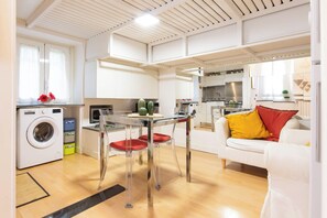 A compact living space with a kitchen, dining area, and a sofa with red cushions. - Casa Orione – Cozy Loft on the Navigli (Milano)