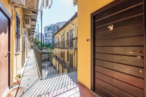 A narrow alleyway with a metal fence, a wooden door, and a building with balconies. - Casa Orione – Cozy Loft on the Navigli (Milano)