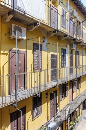 A multi-story building with balconies, air conditioning units, and a yellow facade. - Casa Orione – Cozy Loft on the Navigli (Milano)