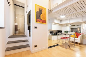 Um apartamento moderno com cozinha, sala de jantar e escada que leva a um banheiro.