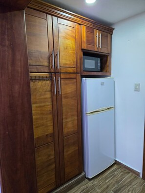 Eine Küche mit Holzschränken, einer Mikrowelle und einem Kühlschrank.