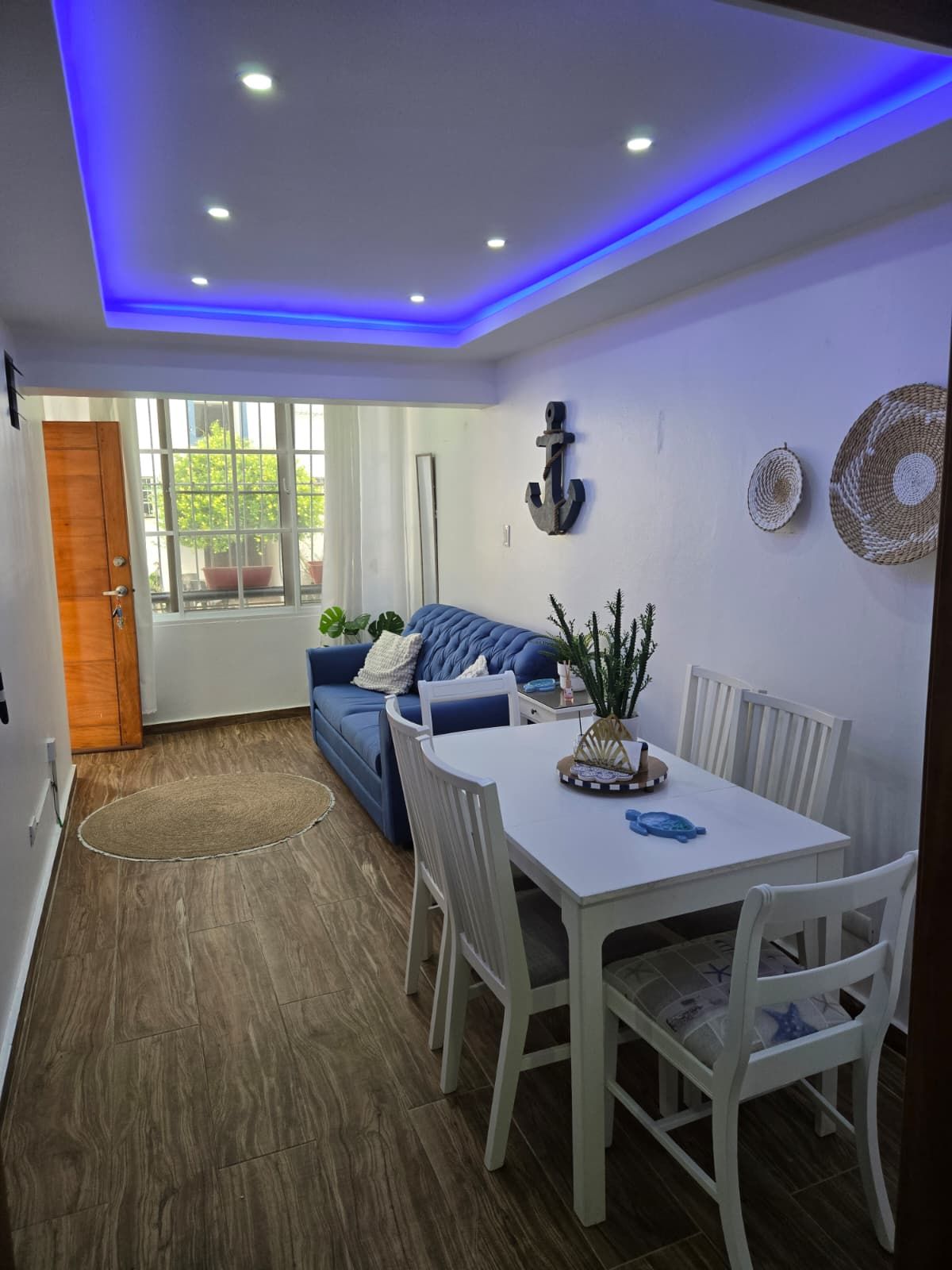 Un salon moderne avec un canapé bleu, une table à manger blanche et des chaises.