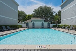 A rectangular swimming pool with a 3 FT depth marking, surrounded by lounge chairs and a small building with a sloped roof. - The Coastal Drift - Communal Pool (Miramar Beach)