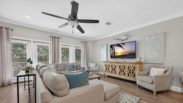 A spacious living room with a ceiling fan, a large flat-screen TV, and a wooden cabinet. - The Coastal Drift - Communal Pool (Miramar Beach)