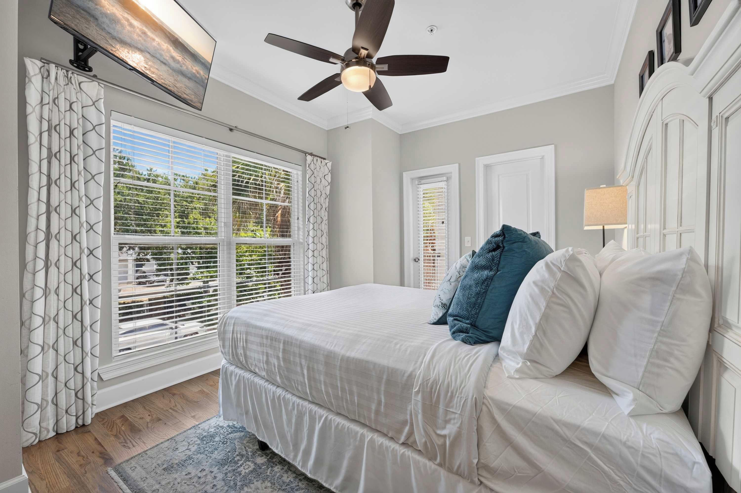 Une chambre à coucher avec un lit, un ventilateur de plafond et une vue sur l’extérieur par la fenêtre.