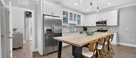 Una cocina moderna con una isla central, electrodomésticos de acero inoxidable y un comedor con sillas.