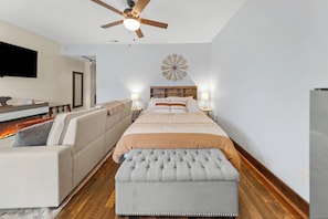 A bedroom with a bed, a sofa, a television, and a ceiling fan. - Bliss Retreat - Whitefish Studio (Whitefish)