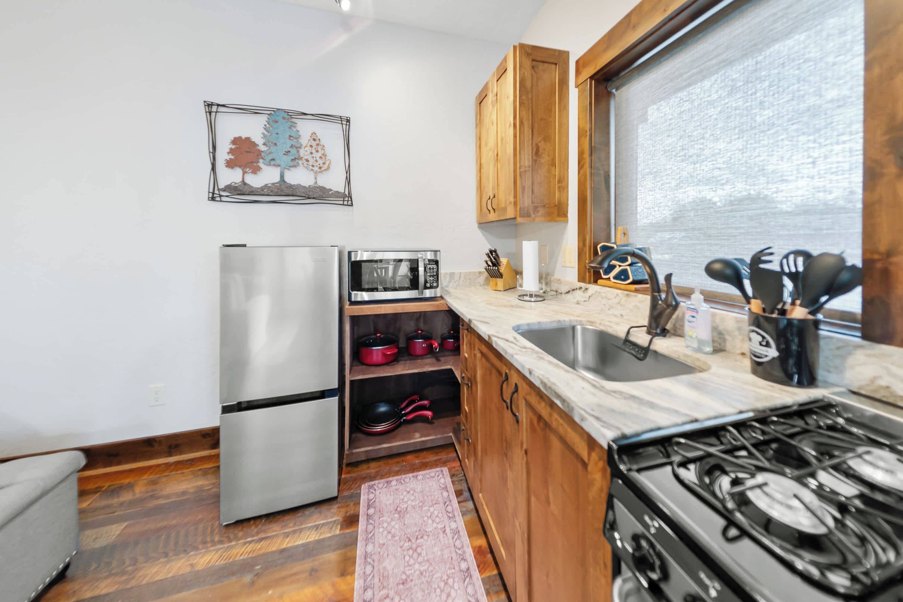 A compact kitchen with a refrigerator, microwave, stove, and wooden cabinets.