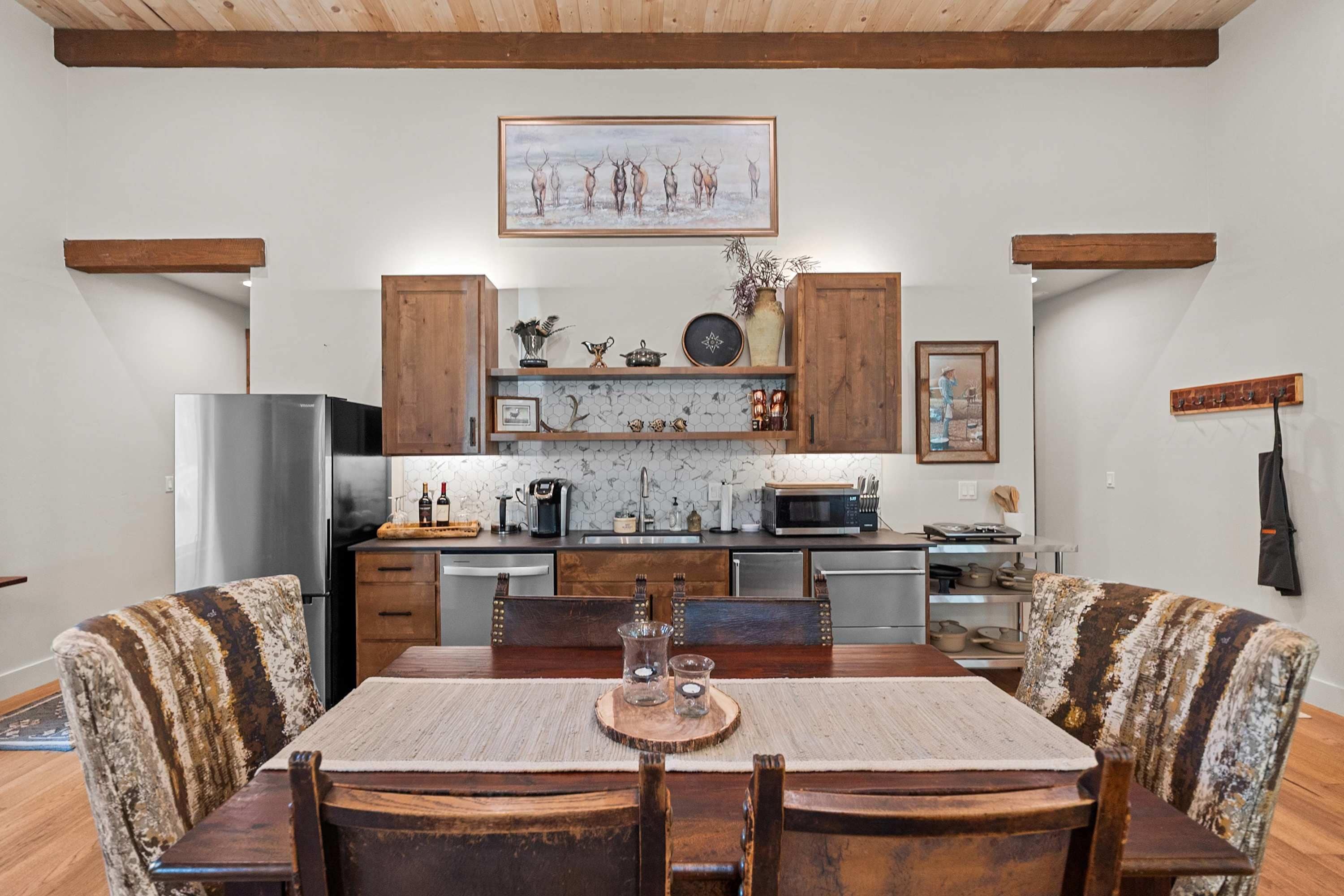 A kitchen with wooden cabinets, a refrigerator, a microwave, and a dining table with chairs.