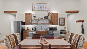 Una cocina con armarios de madera, un refrigerador, un microondas y una mesa de comedor con sillas.