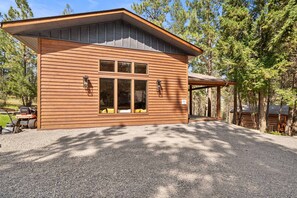 A wooden cabin with a covered porch, large windows, and a gravel driveway. - Whitetail Lodge - Rustic Retreat (Eureka)