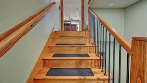 A wooden staircase with black mats at the steps and a metal railing. - Rustic-Chic Barn with 4-Private Suites, 3-upstairs BR's made for Family memories (Montgomery)