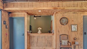 A wooden reception area with a ceiling fan, a clock, and a chair with a cushion. - Rustic-Chic Barn with 4-Private Suites, 3-upstairs BR's made for Family memories (Montgomery)