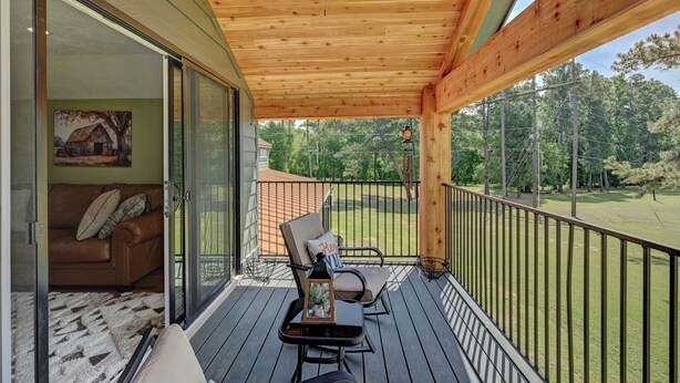 A covered outdoor deck with a ceiling fan, a sofa, a table, and a view of a green landscape. - Rustic-Chic Barn with 4-Private Suites, 3-upstairs BR's made for Family memories (Montgomery)