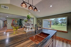 A spacious kitchen with a large window, a sink, and a decorative centerpiece.