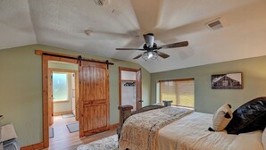 Una camera da letto con un letto, una ventola a soffitto, una porta in legno e una finestra con persiane.