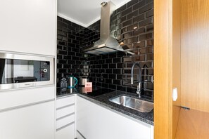 A modern kitchen with a microwave, kettle, and sink. - GuestReady - PoetikBlue - Studio 2 (Porto)