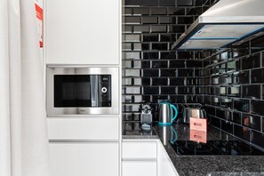 Een moderne keuken met een ingebouwde magnetron, een waterkoker en een koffiezetapparaat op het aanrecht.