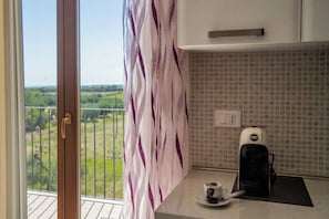 Una cocina con cafetera, taza y vistas a zonas verdes.