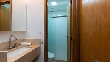 Un baño con lavamanos, espejo e inodoro.