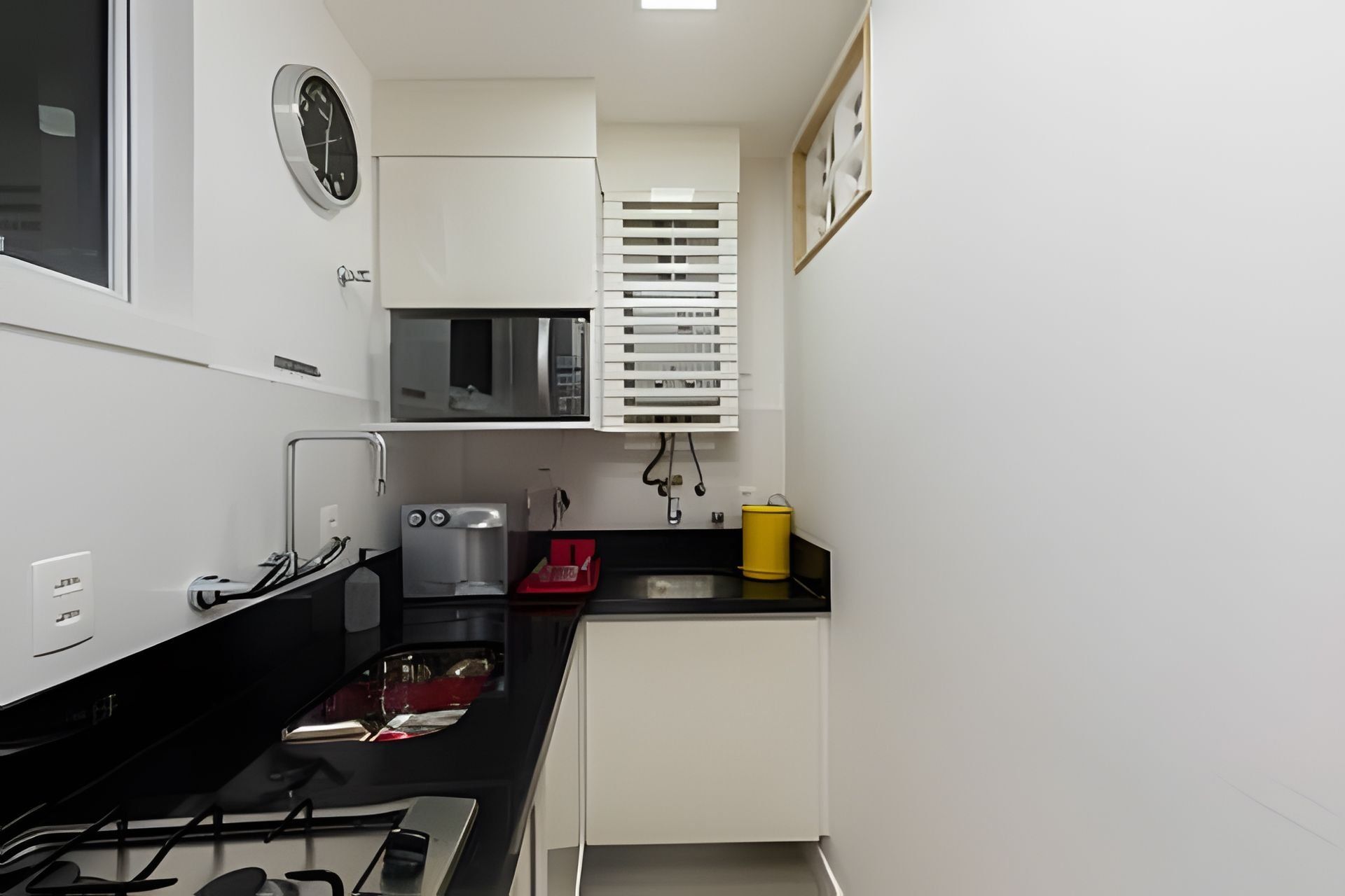 A compact kitchen with a gas stove, a coffee machine, a microwave, and a sink.