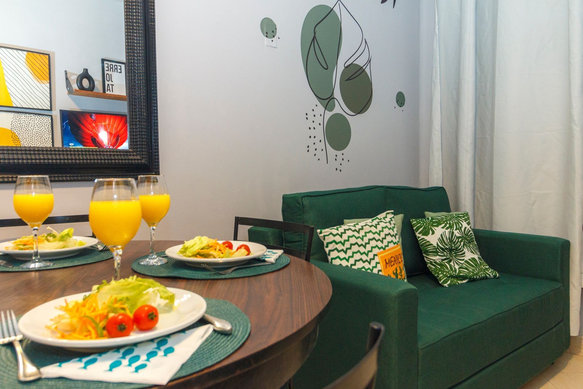 A dining area with a round table, plates of food, and glasses of orange juice.
