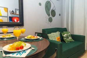 Un comedor con una mesa redonda, platos de comida y vasos de jugo de naranja.