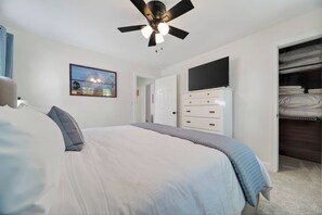 A bedroom with a bed, a ceiling fan, a dresser, a television, and a closet. - Hot Tub + Fire Pit | Steelhead Fishing | Sleeps 6 (Erie)