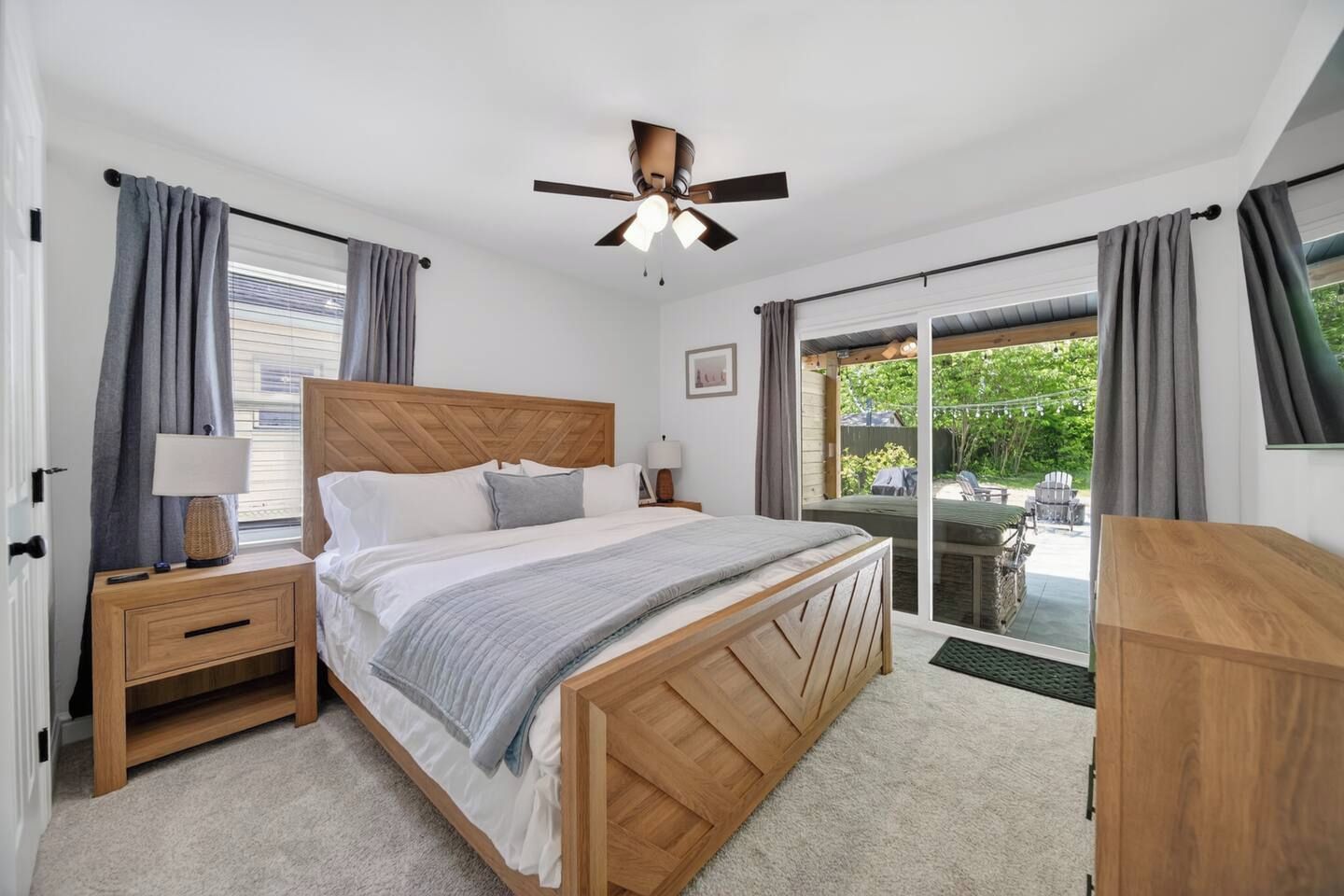 Une chambre à coucher avec un lit en bois, une table de chevet, un bureau et un ventilateur de plafond.