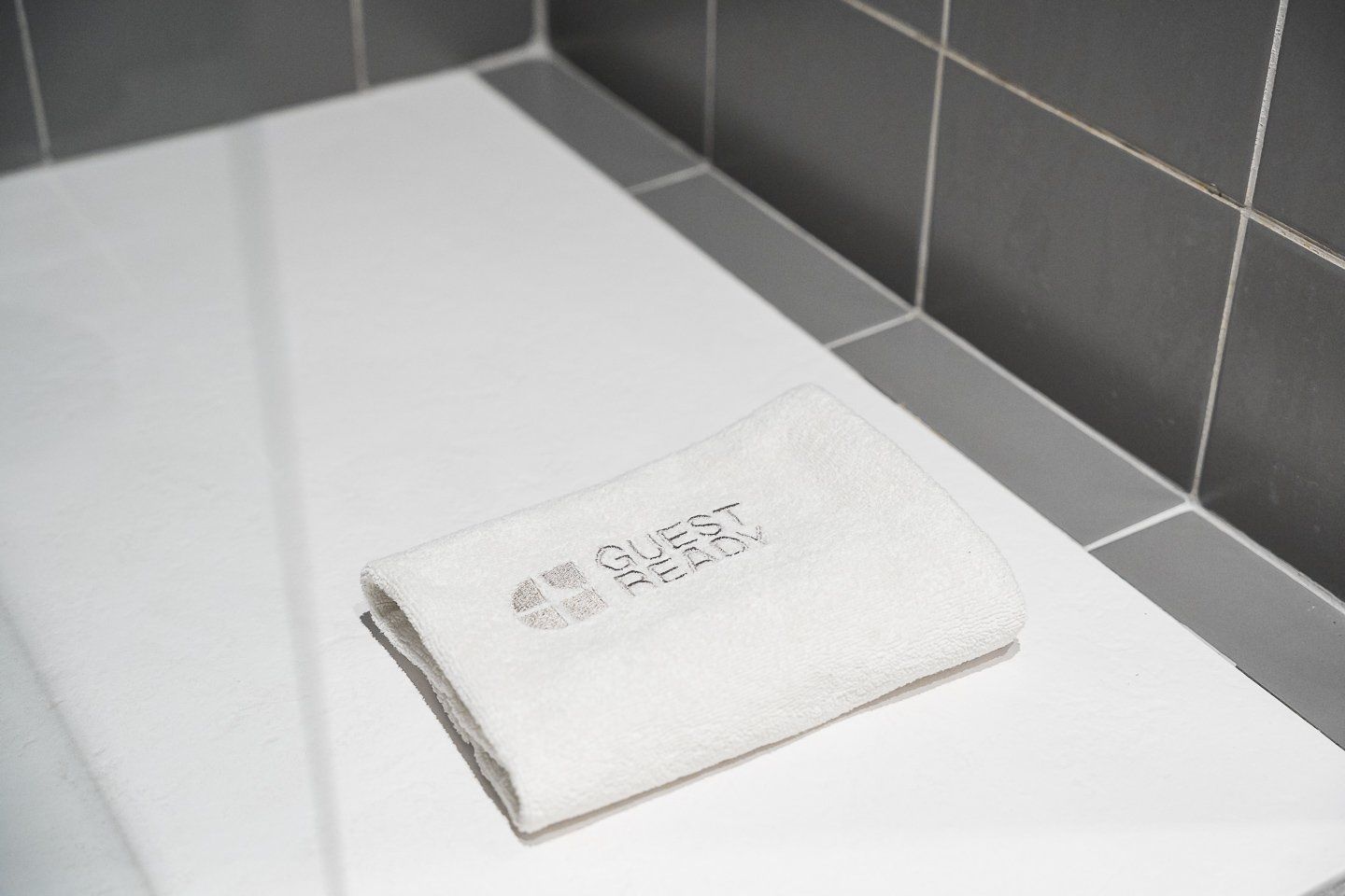 Un asciugamano bianco con la scritta 'GUEST READY' su un lavandino da bagno.
