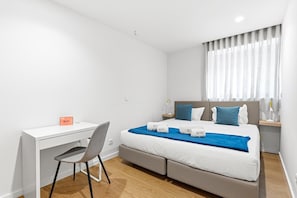 Ein modernes Hotelzimmer mit Bett, Schreibtisch und Stuhl.