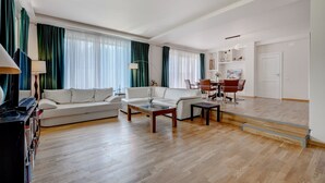 En rummelig stue med sofa, sofabord og spiseplads.