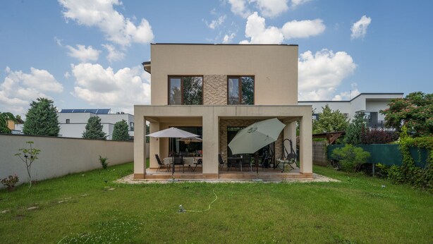 Et moderne hus med to etager og en overdækket terrasse.