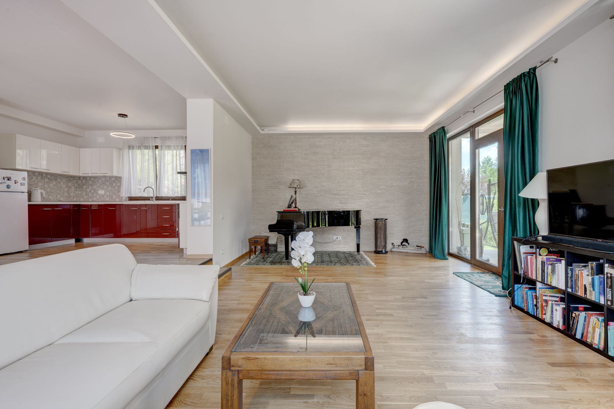 A modern living room with a white sofa, a coffee table with a plant, a fireplace, and a bookshelf.