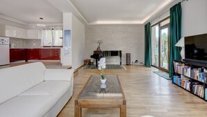 En moderne stue med en hvid sofa, et sofabord med en plante, en pejs og en bogreol.