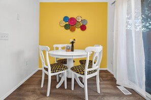 A dining area with a round table, four chairs, a vase with flowers, and a wall decoration of circular objects. - 2BD Townhome Retreat - Close to Downtown & Hiking (Colorado Springs)
