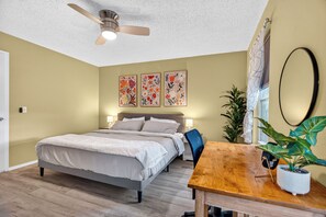 Ein Schlafzimmer mit einem Bett, Nachttischen, einem Deckenventilator und zwei an der Wand befestigten Bildern.
