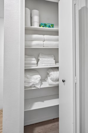 A white closet with shelves holding folded towels and toilet paper. - 2BD Townhome Retreat - Close to Downtown & Hiking (Colorado Springs)