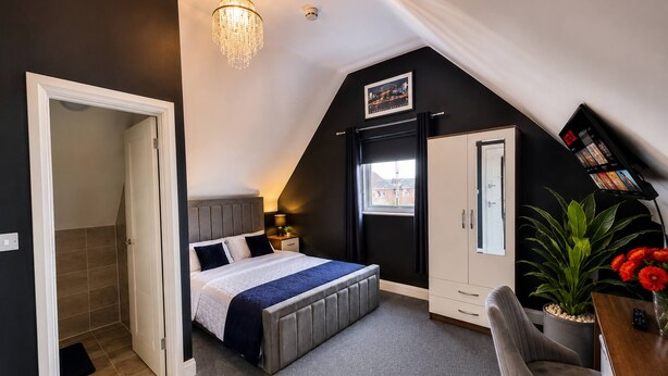 Ein Schlafzimmer mit Bett, Schreibtisch, Kleiderschrank und einer Kandelaber.