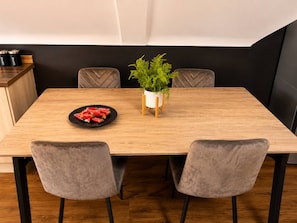 A dining table with a plate of food, two chairs, a potted plant, and a coffee machine in the background. - 4 Bedroom Luxury Apartment in Rushden (Rushden)