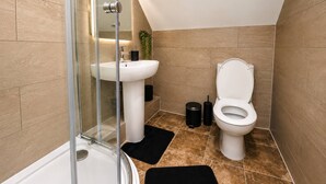 Ein modernes Badezimmer mit Duschkabine aus Glas, einem weißen Waschbecken und einer Toilette.