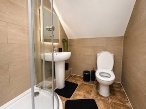 A modern bathroom with a glass shower enclosure, a white sink, and a toilet. - 4 Bedroom Luxury Apartment in Rushden (Rushden)
