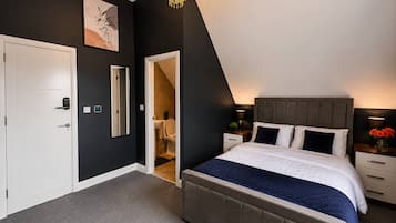 Une chambre à coucher avec un lit, des tables de chevet, une commode, un lustre, une porte et un miroir.
