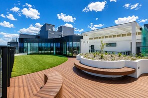 A modern building with a glass facade, a wooden deck, and a landscaped garden area. - Suite Dreams - High-Rise City Views (Box Hill)