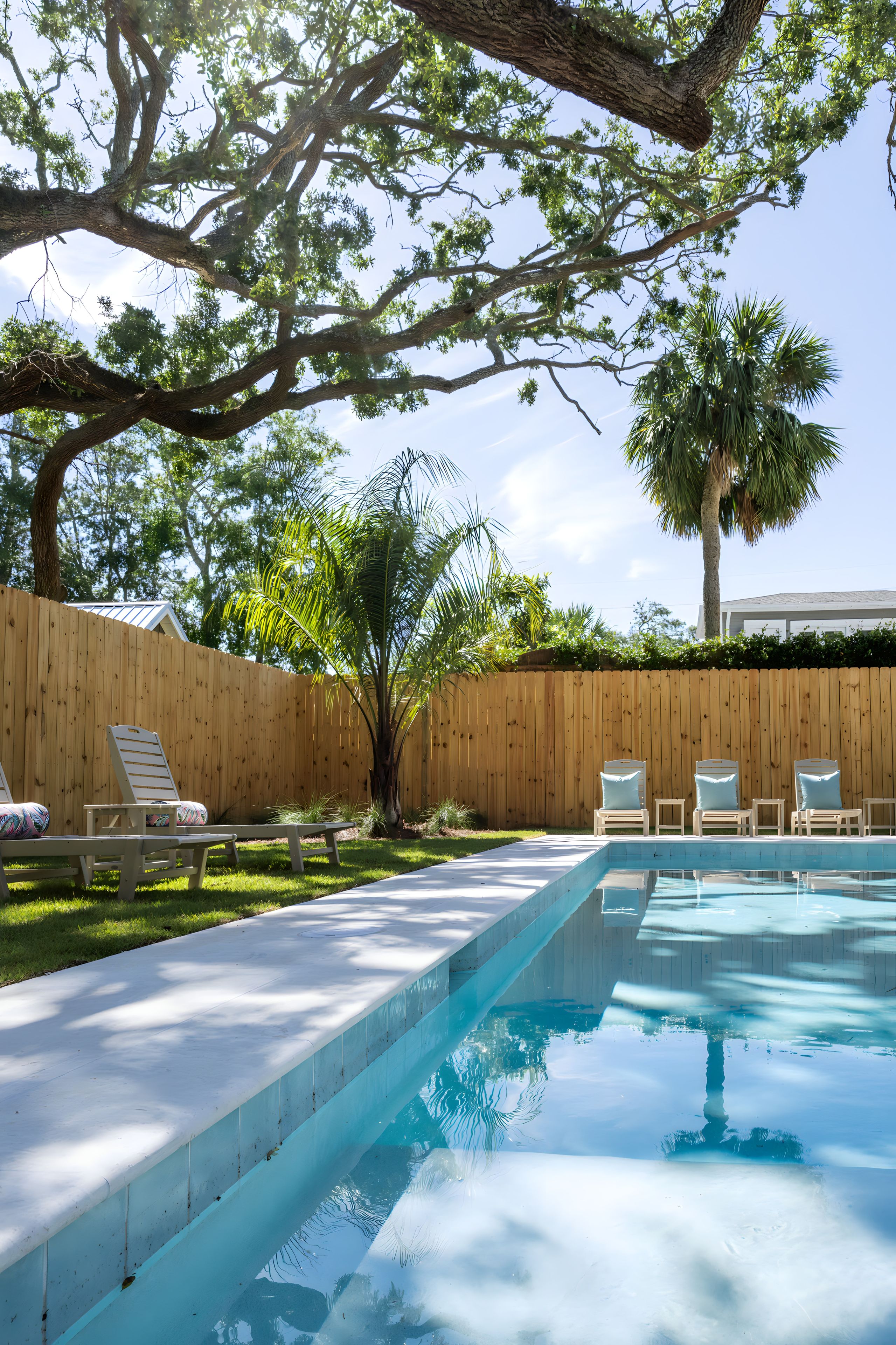 Una piscina con sillas de descanso y una valla de madera.